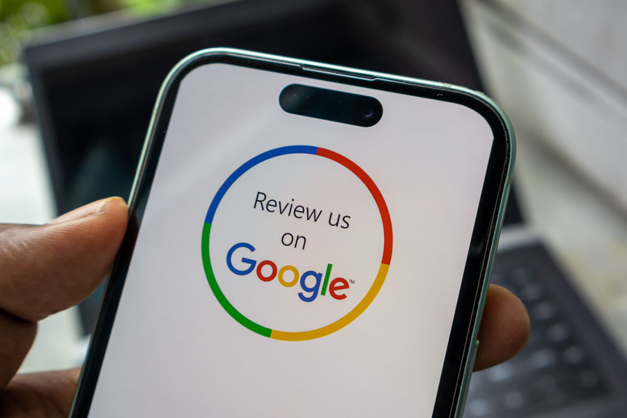 Close up of smartphone screen featuring review us on Google circular emblem. Concept for collecting client feedback and boosting online ratings.